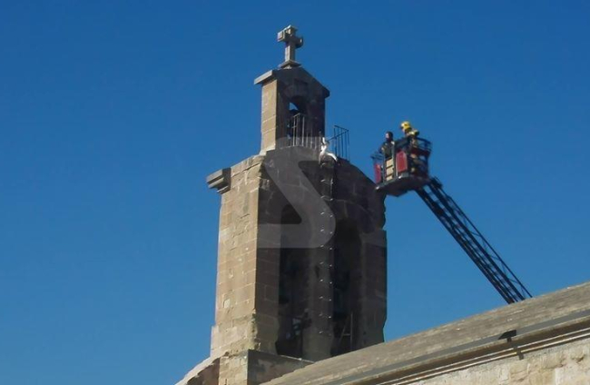 Els bombers, al campanar de la l'església de Sant Martí per rescatar una cigonya atrapada.