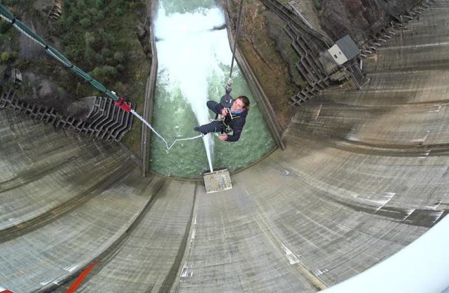Los preparativos para saltar desde lo alto de la presa de la Llosa en esta modalidad llamada ‘bungee’ y un cliente tras efectuar el salto.