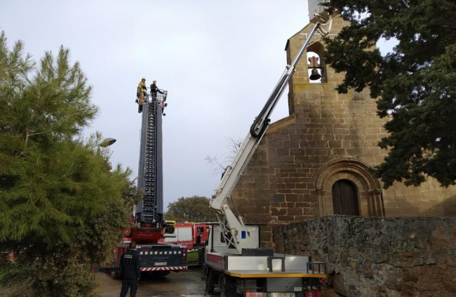 Moment en què els bombers accedeixen a la cistella per rescatar l’operari (esq.) i taca d’oli a la façana de l’església (dr.).