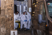 Miembros de los servicios funerarios trasportan uno de los cuatro cadáveres encontrados en una vivienda de Toledo.