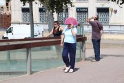 Una mujer se protege del sol con un abanico al cruzar la pasarela Liceu Escolar este verano.