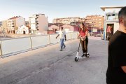 Una usuaria circula con un patinete eléctrico a la pasarela de la estación, donde está permitido hacerlo.