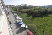 Imagen de la calle Marimunt, sin aceras y con varios coches aparcados junto a un solar con basuras. 