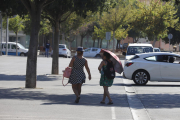 Dos viandantes protegiéndose del sol en Lleida, donde el termómetro superó los 34 grados. 