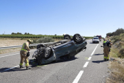 Efectivos de emergencias ayer junto al vehículo, que quedó volcado, en la C-13 en La Sentiu de Sió. 