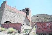 Una pared de ladrillos y una valla metálica impiden el paso hasta los edificios.