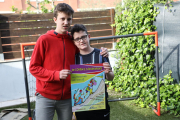 Pau Odina (a la derecha) junto a su hermano Manel, con el cartel de la carrera virtual solidaria. 