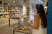 Una lectora hojeando las diferentes opciones literarias de la librería La Fatal, en Lleida.