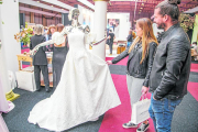 Dos visitantes en uno de los expositores de vestidos de novia.