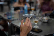 Una dona fuma en una terrassa.