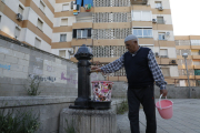 Un veí dels blocs omple una galleda d’aigua en una font.