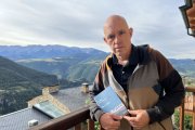 L’escriptor Albert Villaró amb el seu últim llibre, en un balcó d’Estamariu des del qual es veu el Cadí. - ACN / ALBERT L. COBO