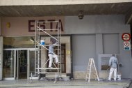 Un operari netejant un embornal a l’interior de l’estació d’autobusos de Lleida i d’altres, pintant la façana del carrer Saracíbar.