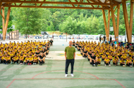 Guardiola, amb els participants del Pep Summer Camp de fons a la pista annexa al camp de futbol de Rialp.