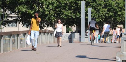 Vianants caminant per Lleida durant el primer dia d'onada de calor