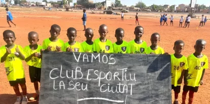 Nens del Centre Djiguiya de Bamako, a Mali, mostren una pancarta de suport al Club Esportiu Ciutat la Seu.