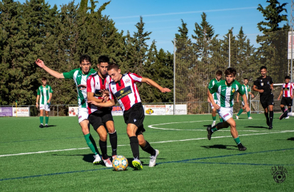 Un jugador del Castellar intenta evitar un company amb la pilota.