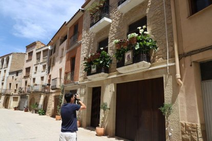 Un jove fotografia balcons engalanats al Soleràs (esquerra). A la dreta, flors al carrer i balcons dels Torms (a dalt) i detall d’una ornamentació al Soleràs. - MAGDALENA ALTISENT