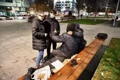 L’Eric i la Mònica, educadors socials, conversen amb dos persones sense llar que ajuden al costat de l’estació de trens. - AMADO FORROLLA