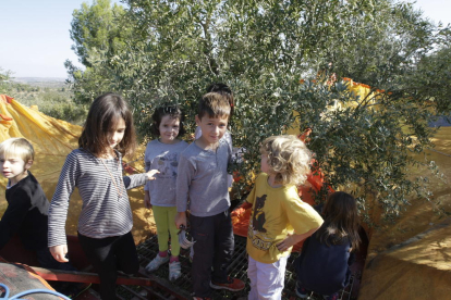 Els més petits es divertien pentinant les branques de les oliveres. A la dreta, la família d’Esteve i Nora, de Barcelona, i a sota, assistents escoltant Benanci.