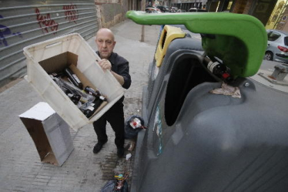 Un empleado de un restaurante de Lleida tirando envases de botellas al contenedor de reciclaje.