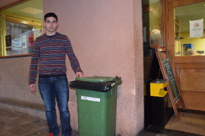 Un empleado de un restaurante de Lleida tirando envases de botellas al contenedor de reciclaje.