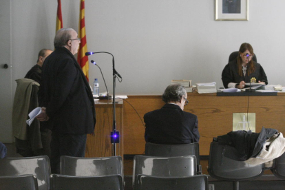 Josep Calbetó, declarando de pie como testigo, y Joan Riu, sentado en el banquillo, en el juicio de ayer. 