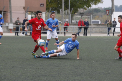 El jugador de l’Alpicat Padrones controla la pilota davant de dos jugadors del Lleida B.
