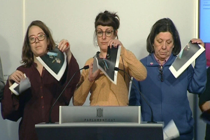 Imagen de televisión de varias diputadas de la CUP en el Parlament que rompen fotografías del Rey, durante una rueda de prensa.
