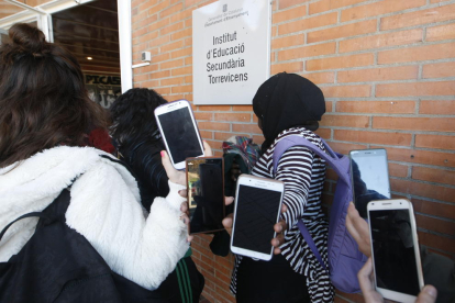 Alumnes del Torre Vicens mostren els mòbils a l’entrada de l’institut.