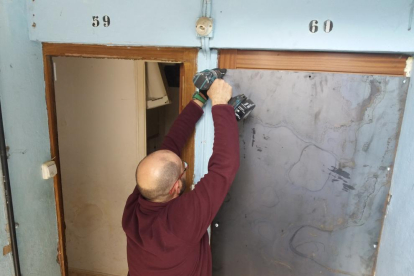 Un operari col·loca una planxa de metall en una porta d’un dels pisos desallotjats.