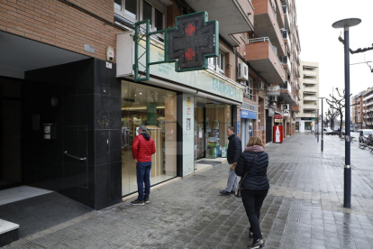Una farmàcia atén a través de la finestreta aquest dilluns a Lleida.