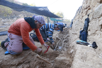 L’equip d’arqueòlegs i antropòlegs treballant a l’excavació, amb diverses rases, i vista de les restes d’un soldat franquista.