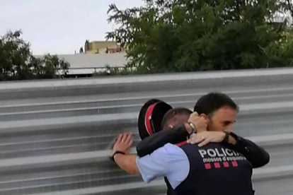 Un hombre consuela a un mosso tras los disturbios en Cappont.