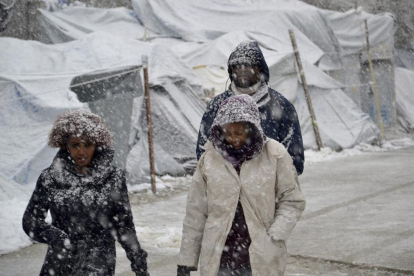 Varios refugiados caminan en un campamento en Lesbos.