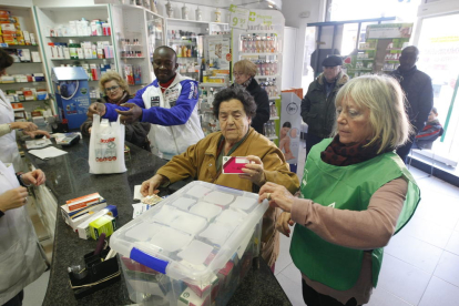 Voluntarios y una clienta solidaria, en la farmacia Isanta Crusellas.