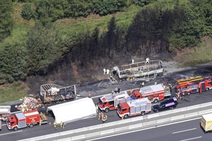 Imagen de las tareas de extinción del incendió tras el choque del autobús con el camión cargado de almohadas y camas.