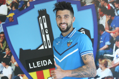 El nuevo jugador del Lleida Esportiu, Marc Trilles, posa ya con la equipación del club y junto al escudo.