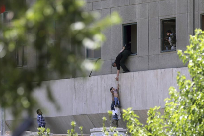Policías iraníes ayudan a escapar a civiles después de que hombres armados entraran en el Parlamento.