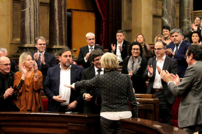 La diputada y exconsellera Irene Rigau, de espaldas, saluda al Govern mientras recibe una ovación en pleno del Parlament.