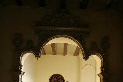 Uno de los salones de la casa señorial Duran i Sanpere de Cervera y, a la derecha, la capilla privada del edificio, con los personajes de las pinturas inspirados en la propia familia.