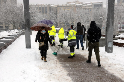 Operarios de limpieza barrían la nieve de la pasarela del Liceu Escolar de Lleida. 