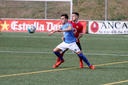 Un jugador del Lleida Esportiu B pugna pel control de l’esfèrica davant de dos rivals sota l’atenta mirada del col·legiat.