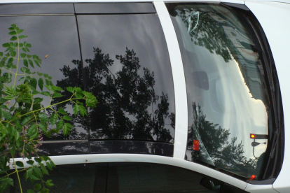 Foto artistica dels reflexos de primavera, de les fulles dels abres, en el vidre d'un cotxe