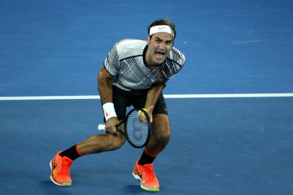 Roger Federer besa el trofeu aconseguit a Melbourne amb Rafa Nadal al fons de la imatge.