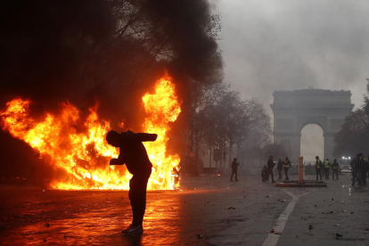Un grup d’‘armilles grogues’ (‘gilets jaunes’) s’enfronten a la policia antiavalots prop de l’Arc de Triomf a París.