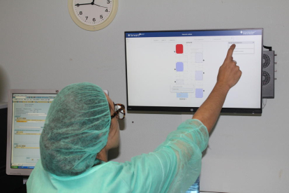 Un infermer col·loca una polsera de geolocalització a un pacient mentre una altra infermera inspecciona l’estat dels quiròfans que ja utilitzen aquesta tecnologia.