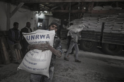 Un refugiado palestino lleva un saco con harina en un campamento de refugiados de Gaza.