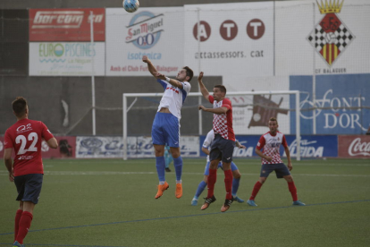 Un jugador del Mollerussa intenta controlar una pilota de cap davant de l’oposició d’un rival del Balaguer.