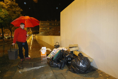 Un veí de Ciutat Jardí amb el cubell observa l’acumulació de bosses al costat del seu edifici.